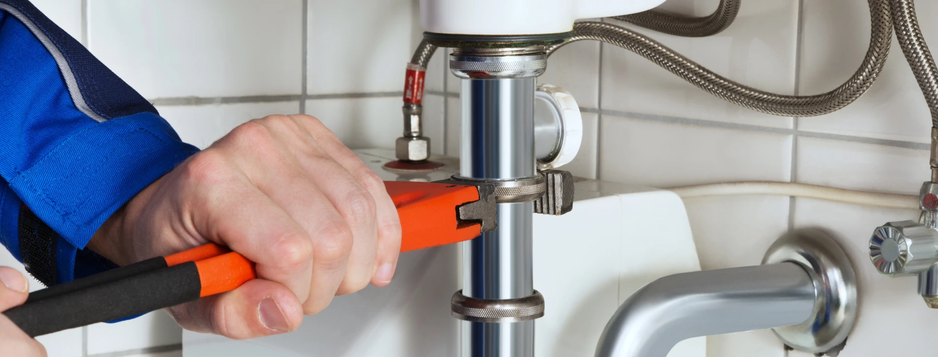 A plumber carries out maintenance in a washroom.