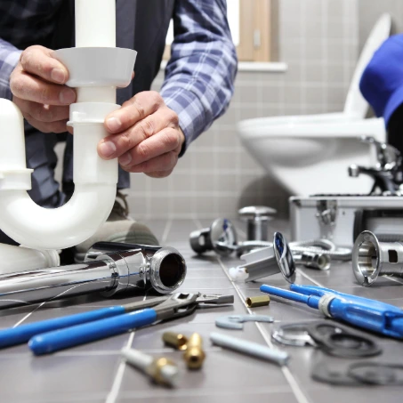 A plumber lays out all of his tools while fixing a toilet.